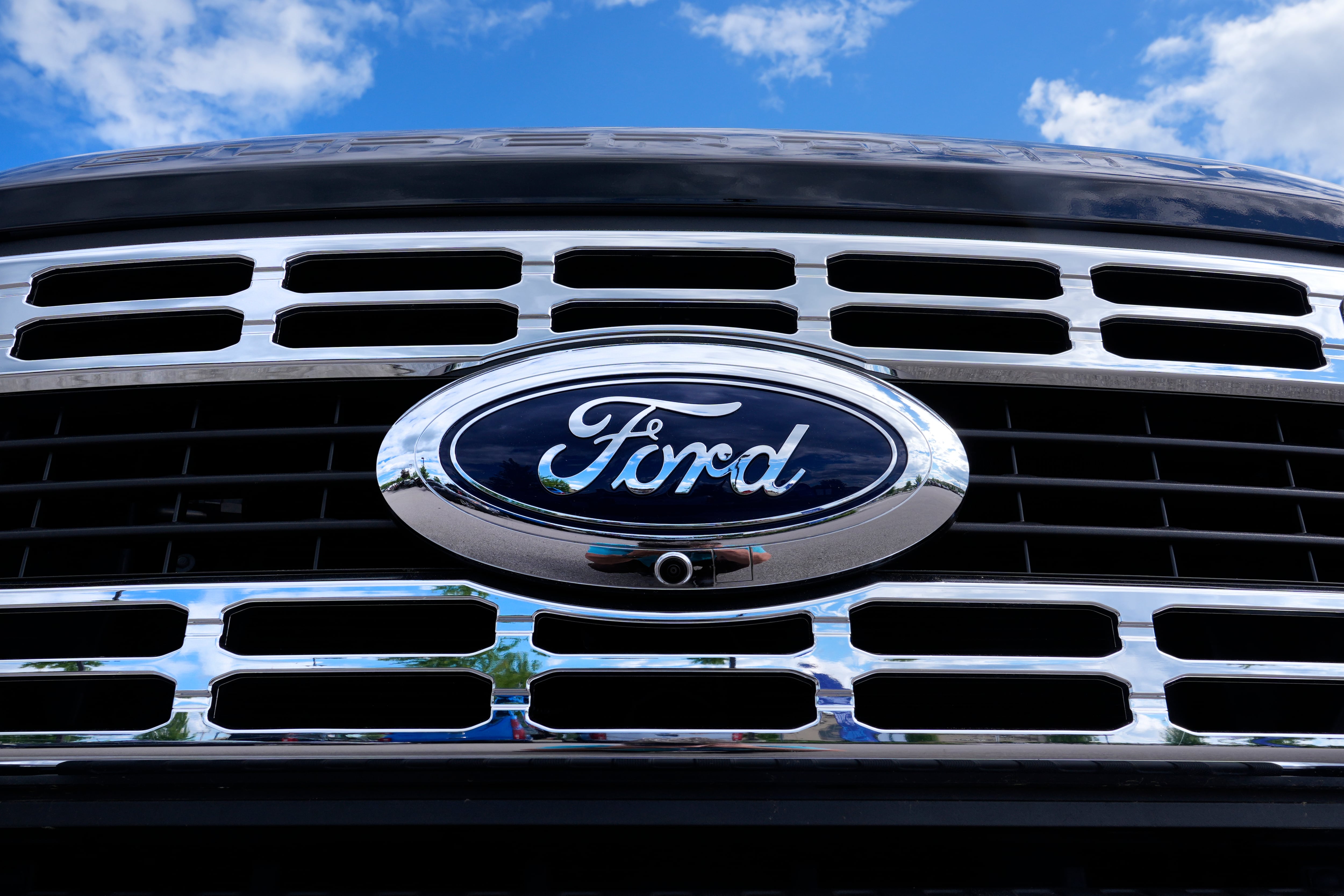 The Ford logo is shown on the grill of a pick-up truck on a dealership lot in Salem, New Hampshire.