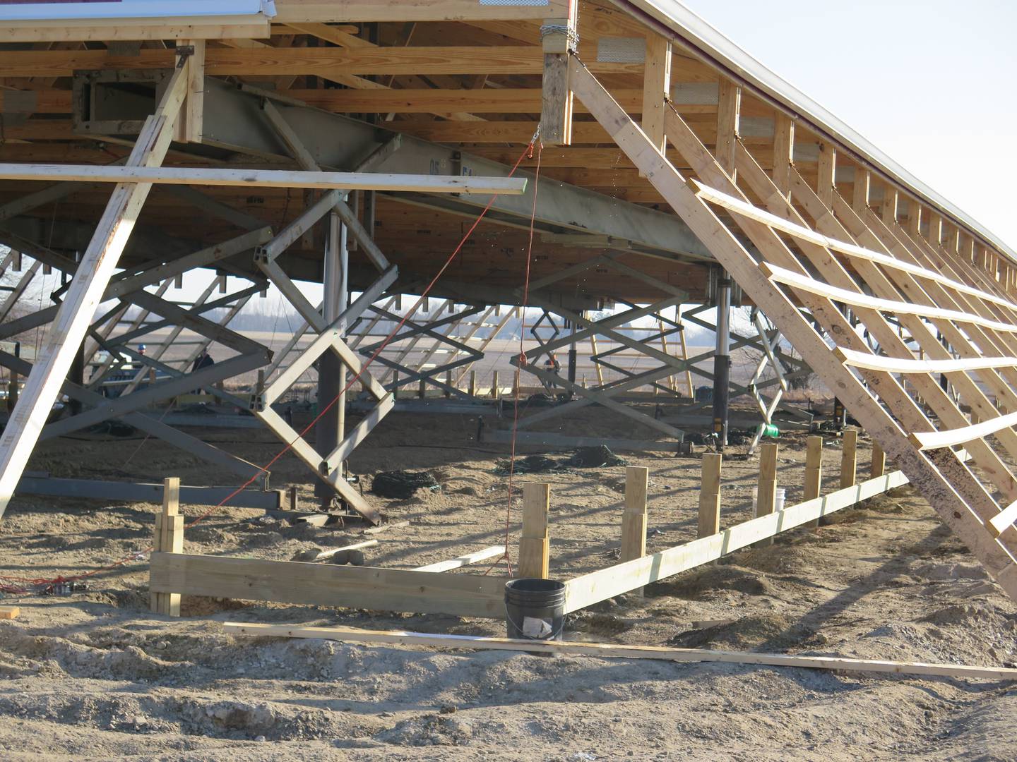 Eight hydraulic lifts connected to steel beams synchronously raise the roof as the hinged wall columns move inward toward the ground base of the barn.