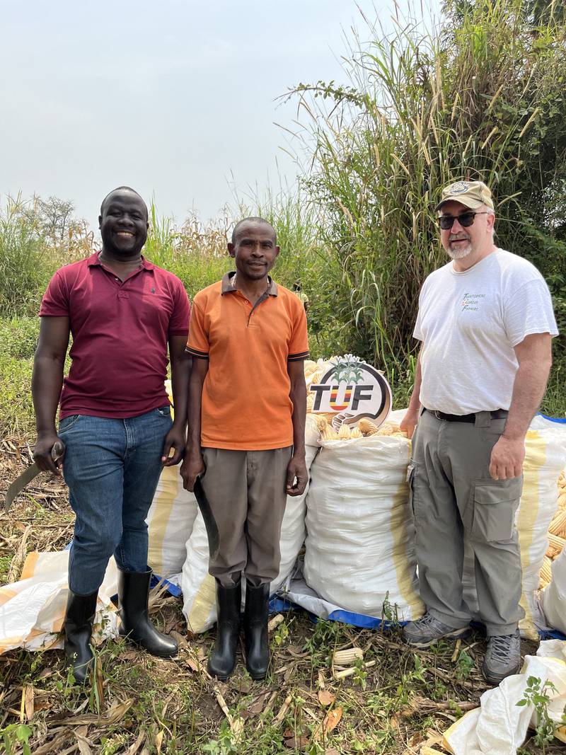 Peter Baguma (from left), a Ugandan farmer and Joe Schmidt show bags of maize that was harvested by TUF farmers. Through the Transforming Ugandan Farmers program, farmers in Uganda are learning how to grow better crops through training and the use of improved seeds and fertilizers.