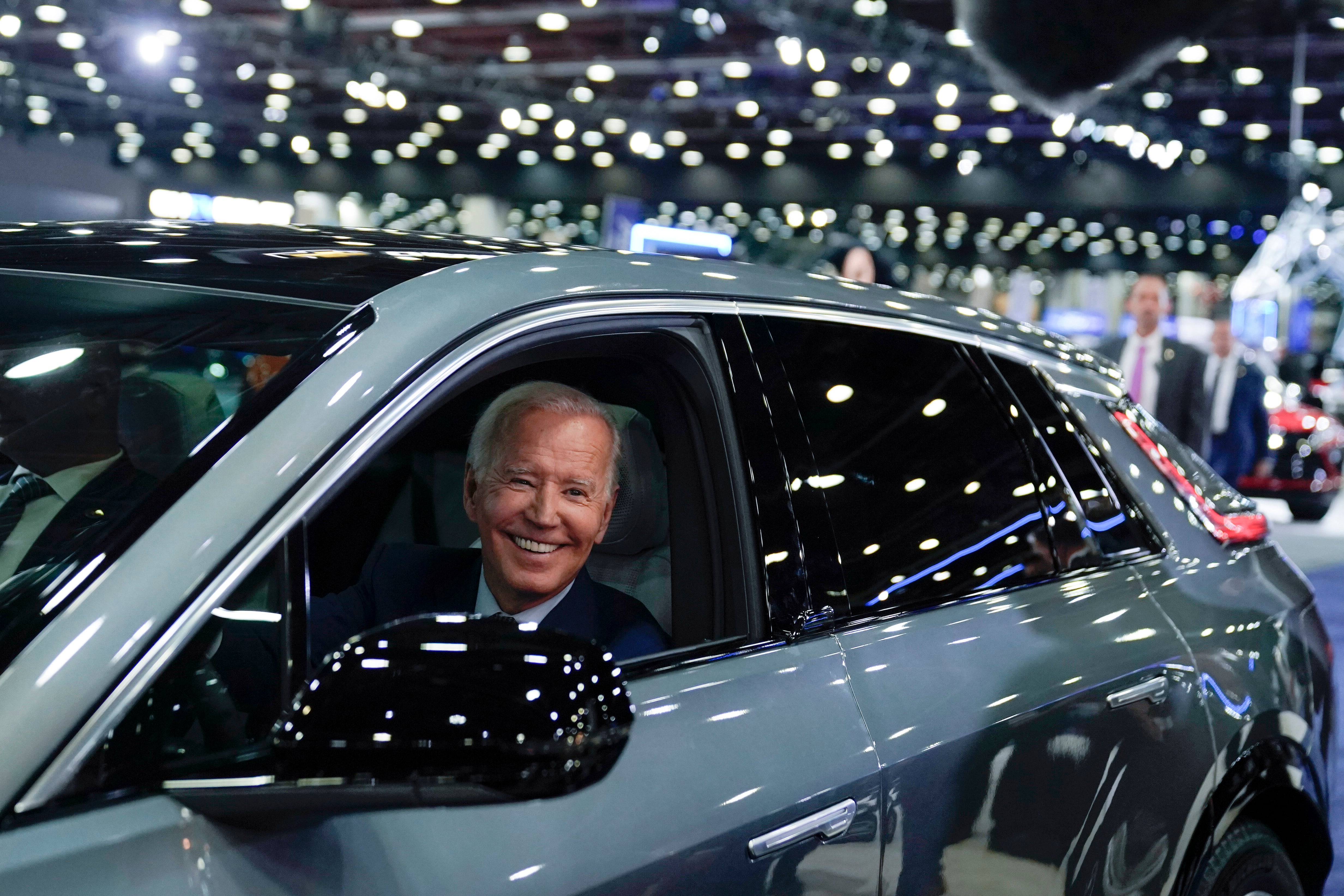 President Joe Biden drives a Cadillac Lyriq through the showroom during a tour at the 2022 Detroit Auto Show.