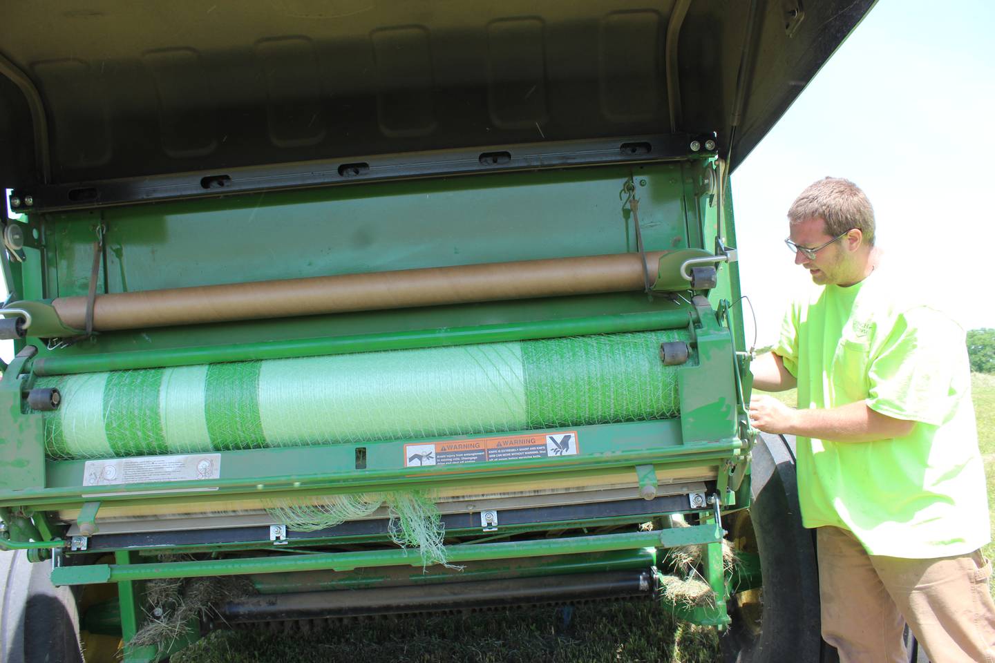 Mitchel Rahn makes adjustments to the net wrapping on the round baler. In addition to round bales, the northwestern Illinois farmers make small and large square bales and most of their hay is sold to customers within 45 miles of the farm.