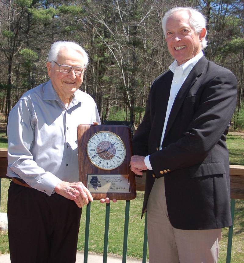 Lowell Akers (left) was recently named to the Illinois Society of Professional Farm Manages and Rural Appraisers Hall of Fame. A plaque marking the fete was presented to him by Russ Hiatt, Hiatt Farmland Services, Champaign, immediate-past president of the society.