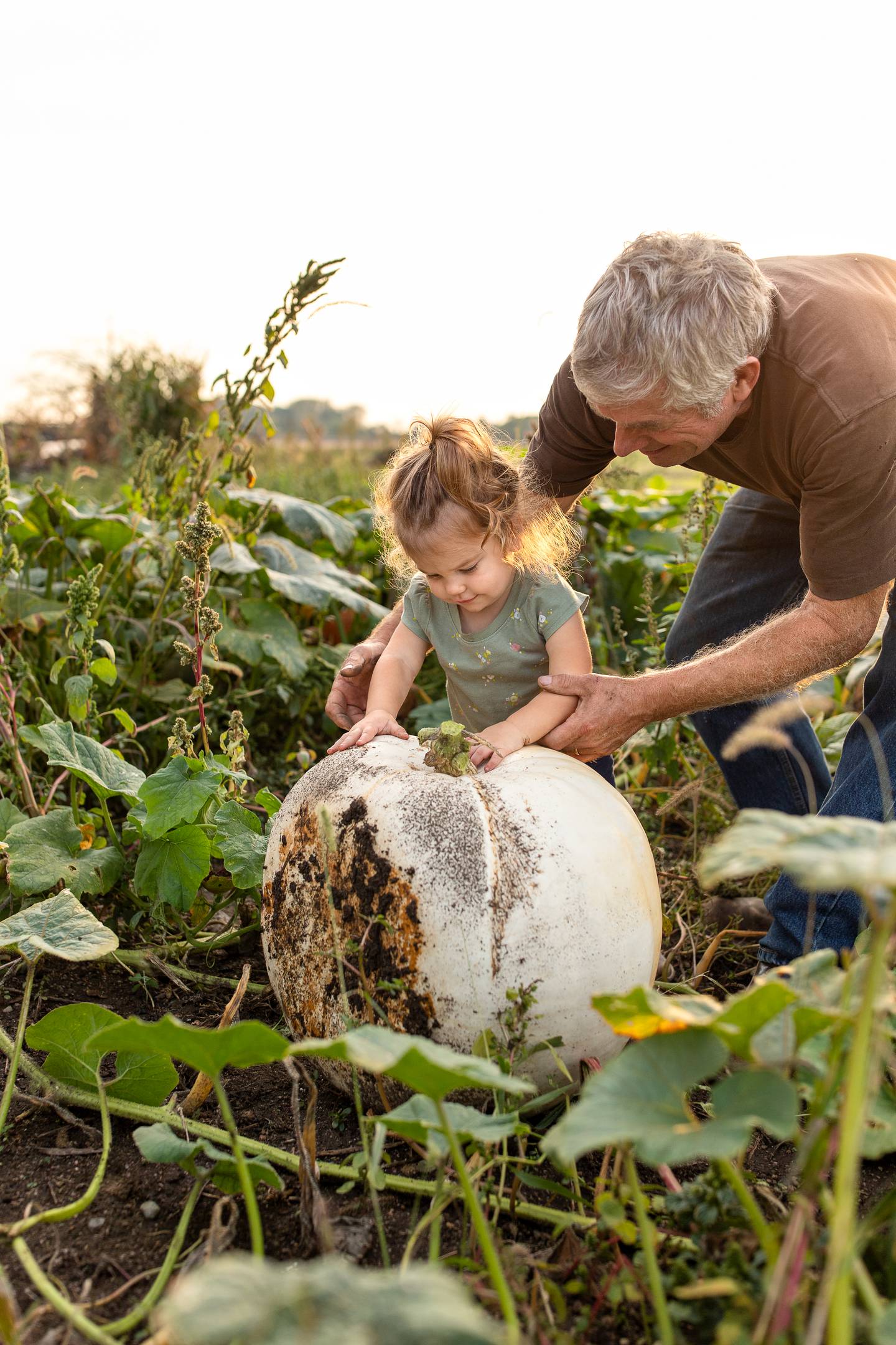 A young girl picks a white pumpkin. The photographer, April Lamb, won second place in the inaugural 2023 INFB Photo Contest.