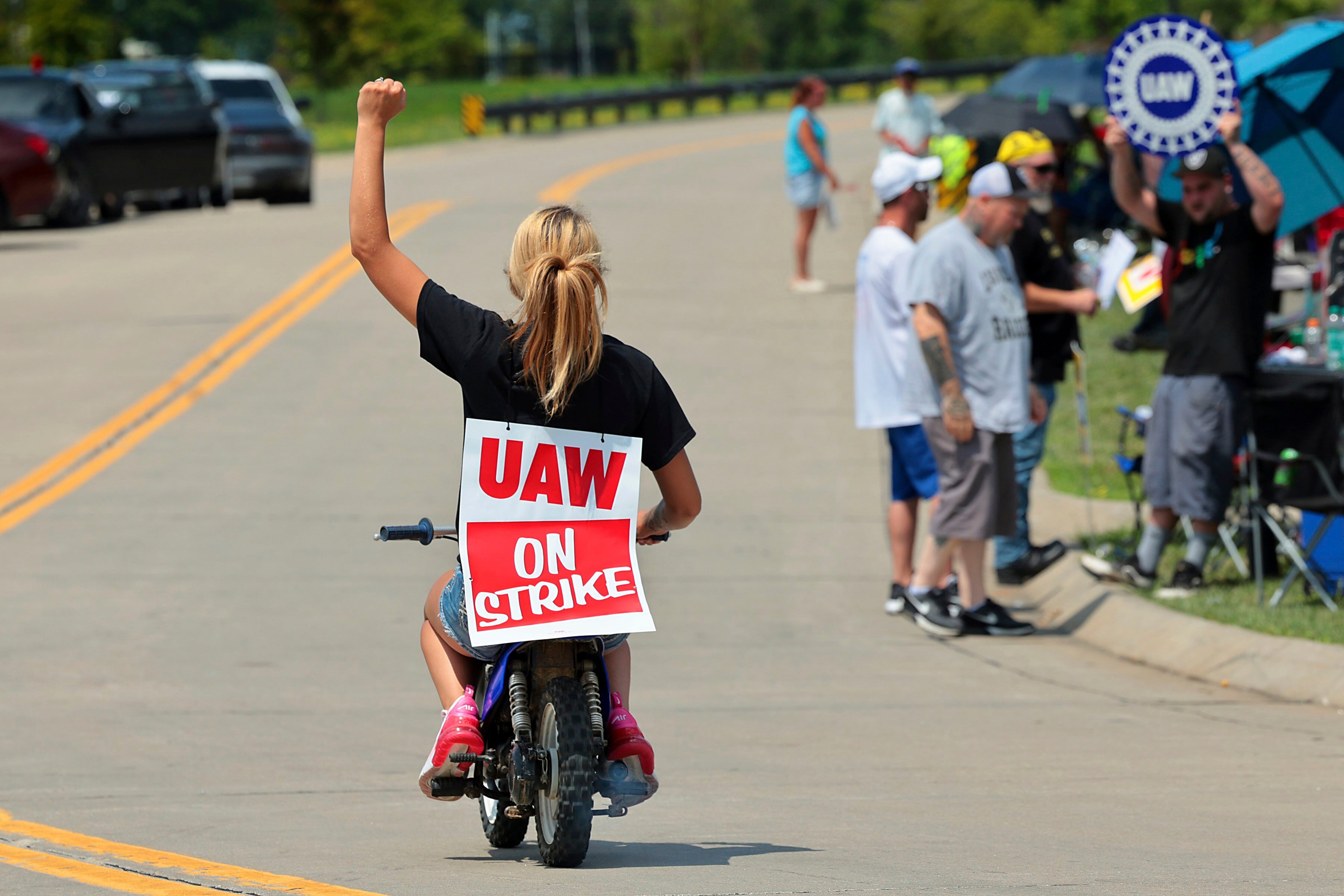 Lear production worker Abigail Fletcher rides her mini bike in support of the picket line as members of United Auto Workers Local 282 continue their strike against the car and truck seat manufacturer in Wentzville, Mo. on Tuesday, July 23, 2024. The strike led to a shutdown at the nearby GM assembly plant. (Robert Cohen/St. Louis Post-Dispatch via AP)