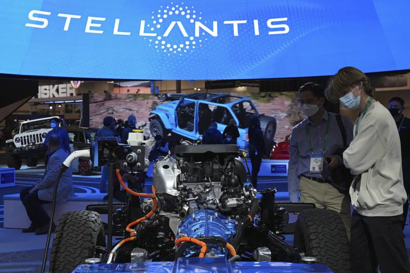 FILE - People look at the charging technology from the Jeep Wrangler 4xe at the Stellantis booth during the CES tech show Thursday, Jan. 6, 2022, in Las Vegas.  (AP Photo/Joe Buglewicz, File)