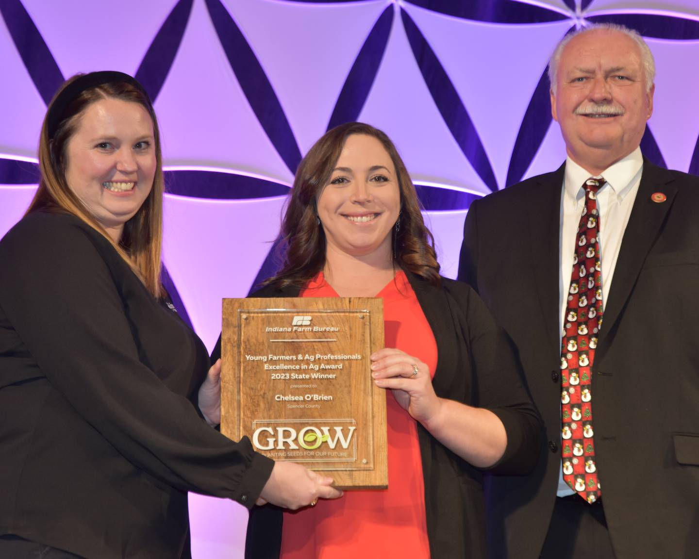 Winning the Excellence in Agriculture Award, which honors Indiana Farm Bureau members who do not derive the majority of their income from a farming operation, but who actively contribute and grow their involvement in Farm Bureau, the agriculture industry and other community organizations, Chelsea O’Brien will receive an $11,000 cash prize and an all-expenses-paid trip to Salt Lake City in January to compete at the American Farm Bureau Federation Annual Convention and Trade Show. She received the award from Hilary Poulson (left), Growing Forward specialist from Farm Credit Mid-America, and INFB President Randy Kron at the INFB State Convention.