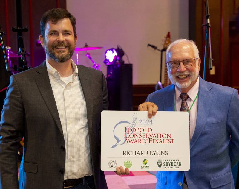 Richard Lyons (right) accepts a finalist sign from Lance Irving, director of the Leopold Conservation Award Program, during the Association of Illinois Soil and Water Conservation Districts’ Summer Training Conference and 76th Annual Meeting. Other finalists are Martin Family Farms and Lieb Farms. The award recipient will be revealed at the Illinois State Fair.